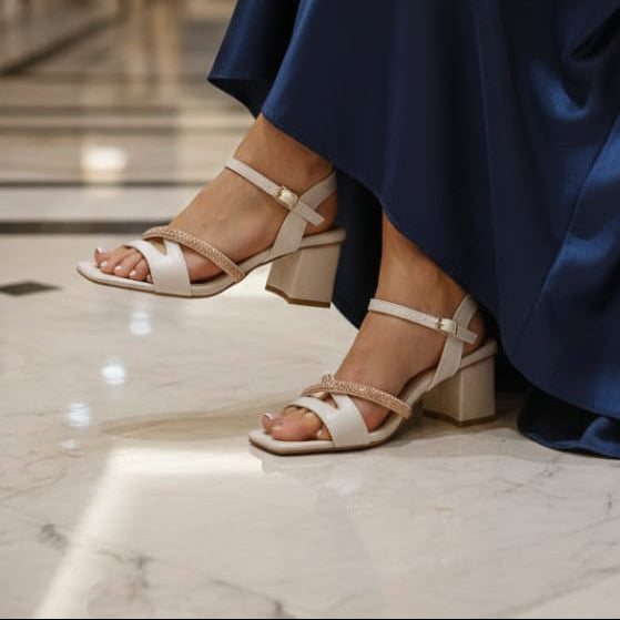 Person wearing a blue satin dress and white sandals in an elegant indoor setting.