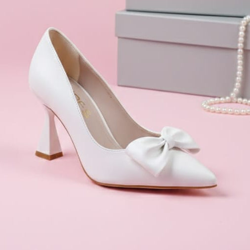 White high-heeled shoe with a bow on a pink background