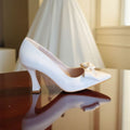 White wedding dress and shoes on a reflective surface with a blurred background