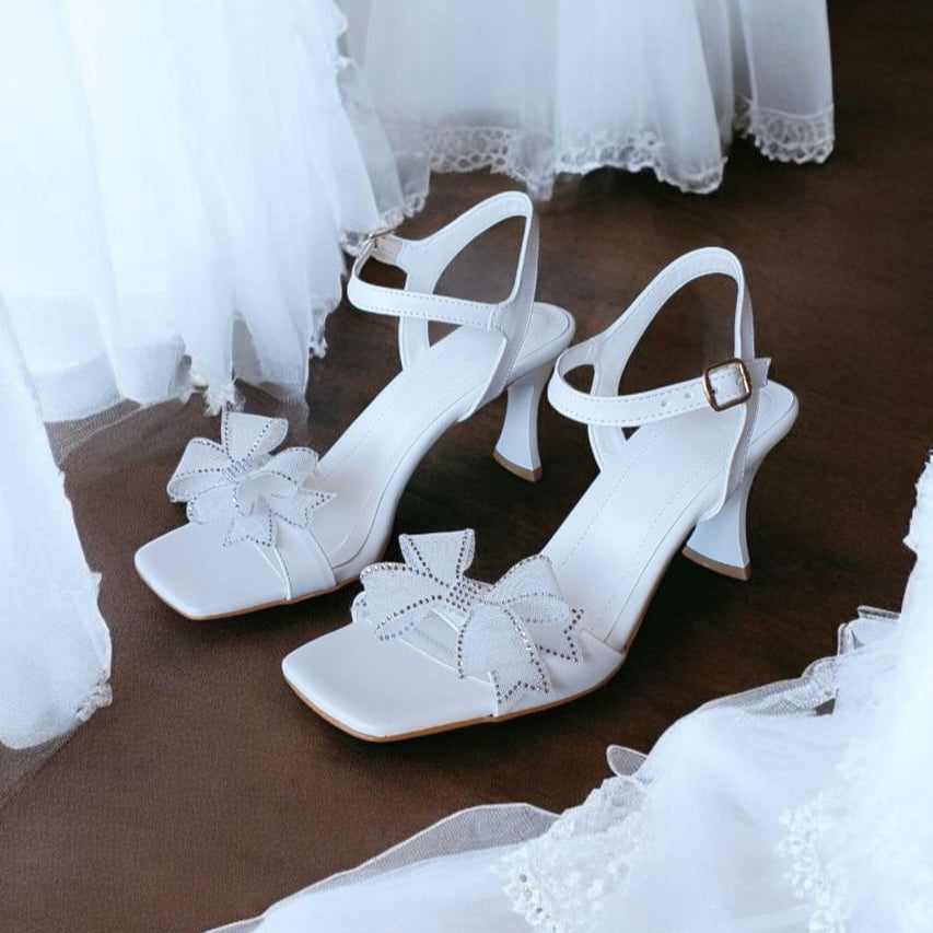White bridal heel sandal with ankle strap, crystal-trimmed mesh bow, flared 7 cm heel and square toe—elegant wedding shoe beirut